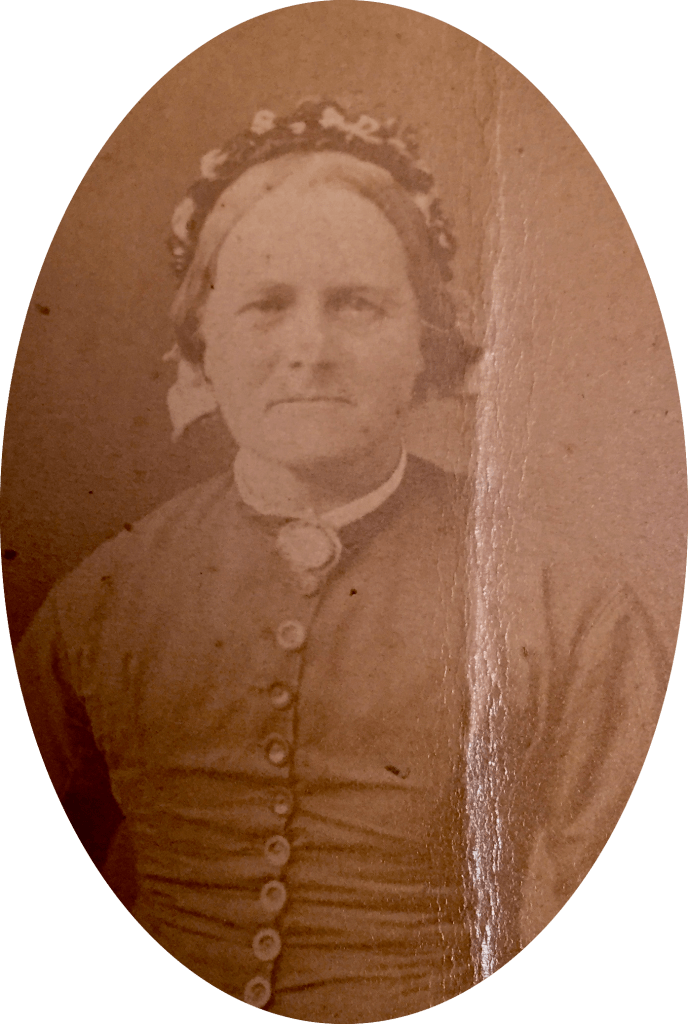 Carte de Visit photograph of a middle aged woman from the 1880s. She is wearing a buttoned tunic and a hat or bonnet.