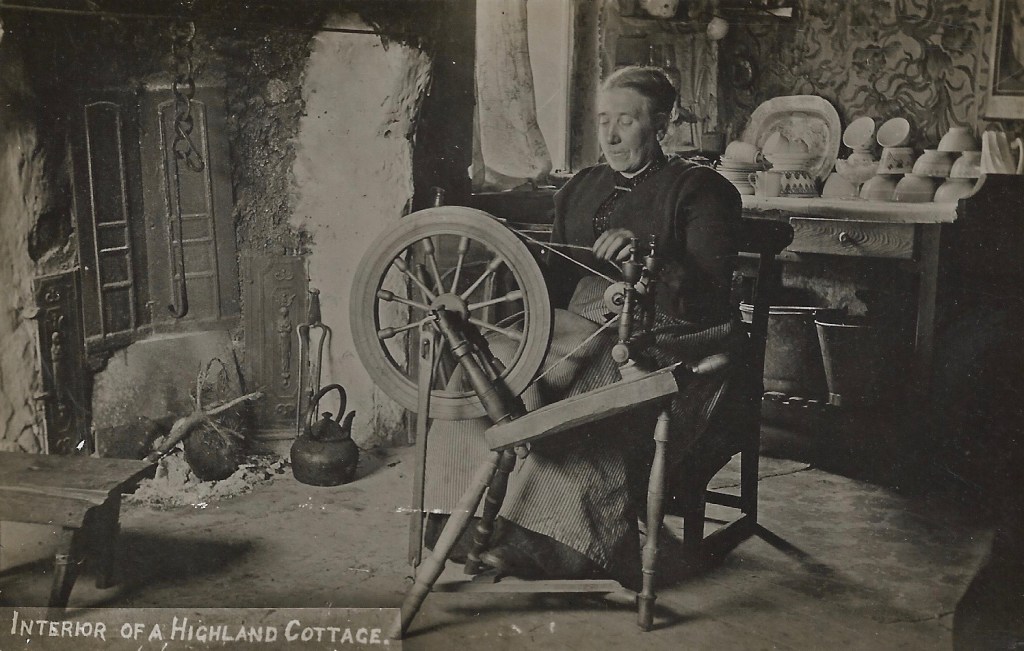 An older woman sits on a wooden chair working on a wooden spinning wheel. Behind her is a wooden dresser which holds plates and bowls. To the right is the fireplace with a metal hook and kettle. Nearby is a small wooden bench.
